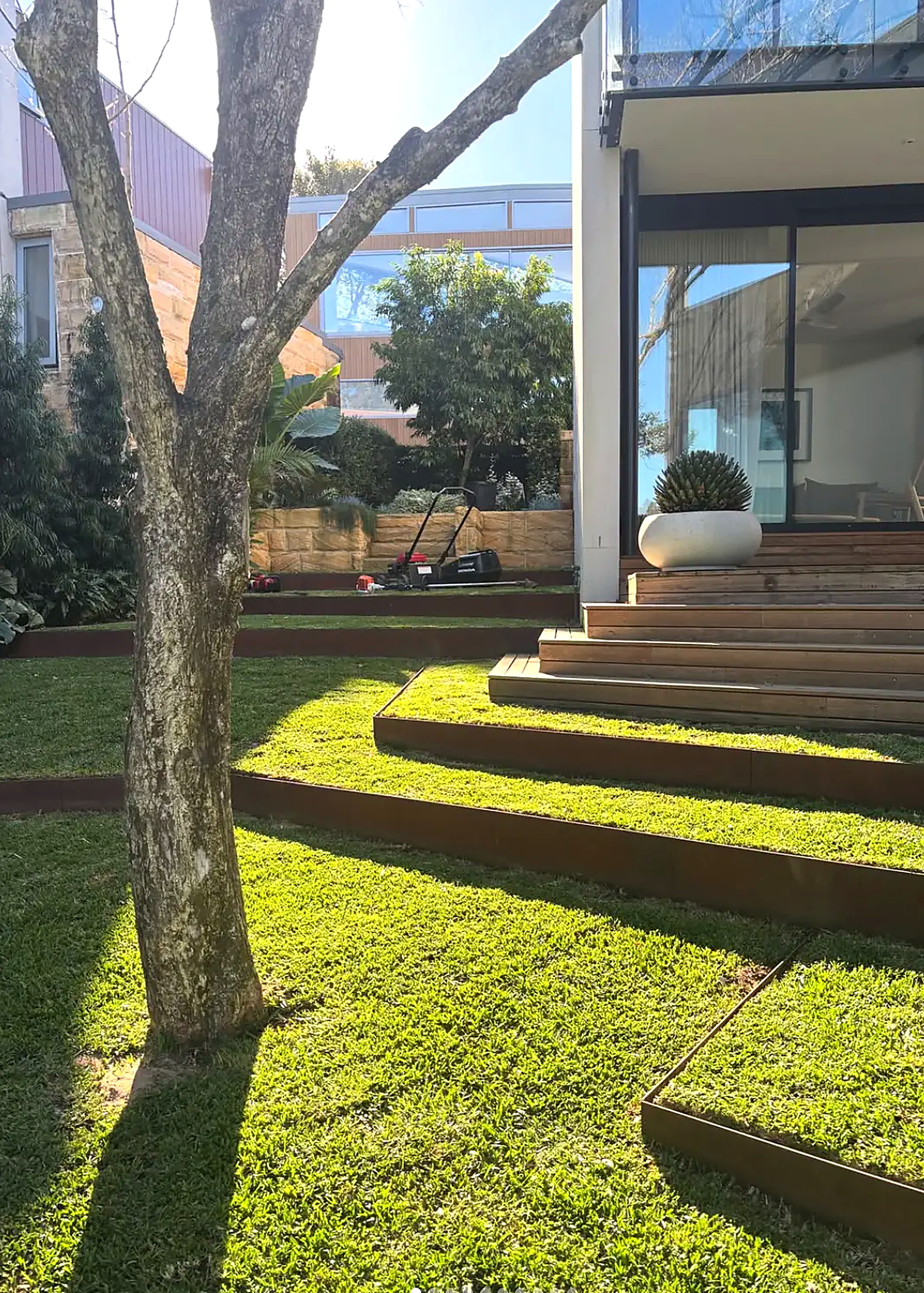 Terraced lawn with corten steel steps beside a modern Sydney home